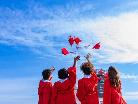Four students throwing their red caps in the air