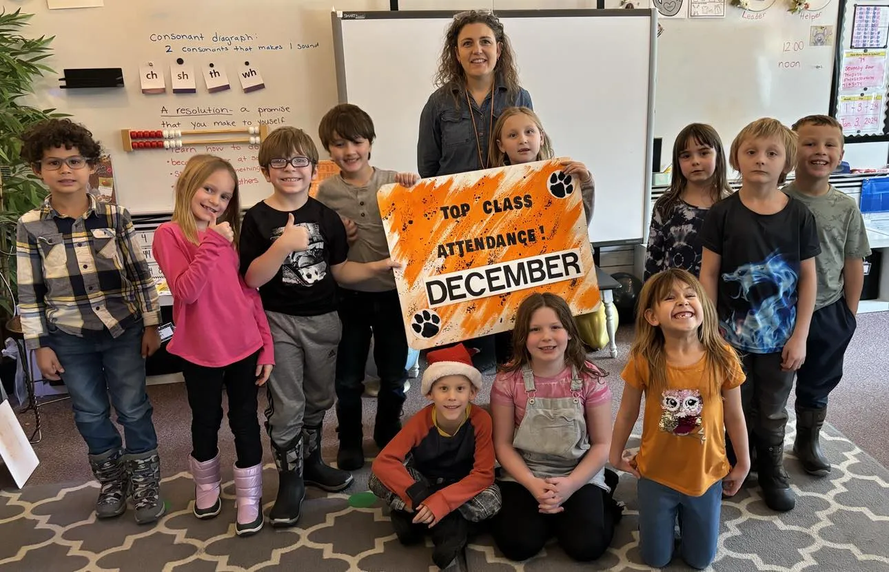 Classroom of teacher and students holding a top attendance sign